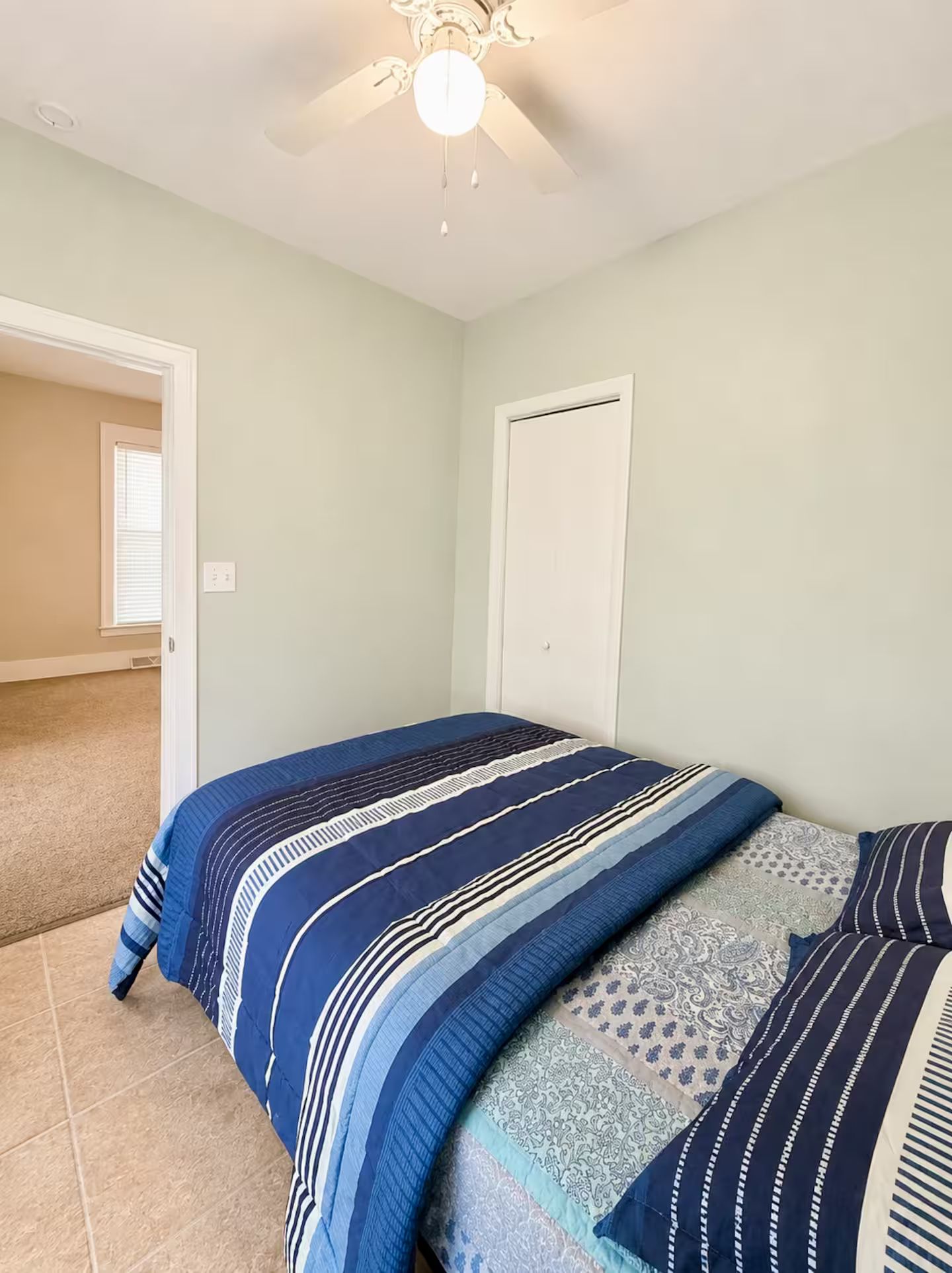 Ein Schlafzimmer mit einem Bett, einem Deckenventilator und einer Tür.