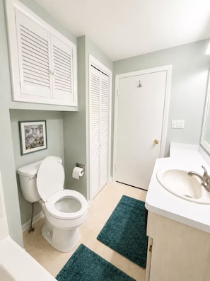Un bagno con il water, un lavandino e due porte.