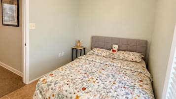 A bedroom with a bed, a ceiling fan, a nightstand, and a window with blinds.
