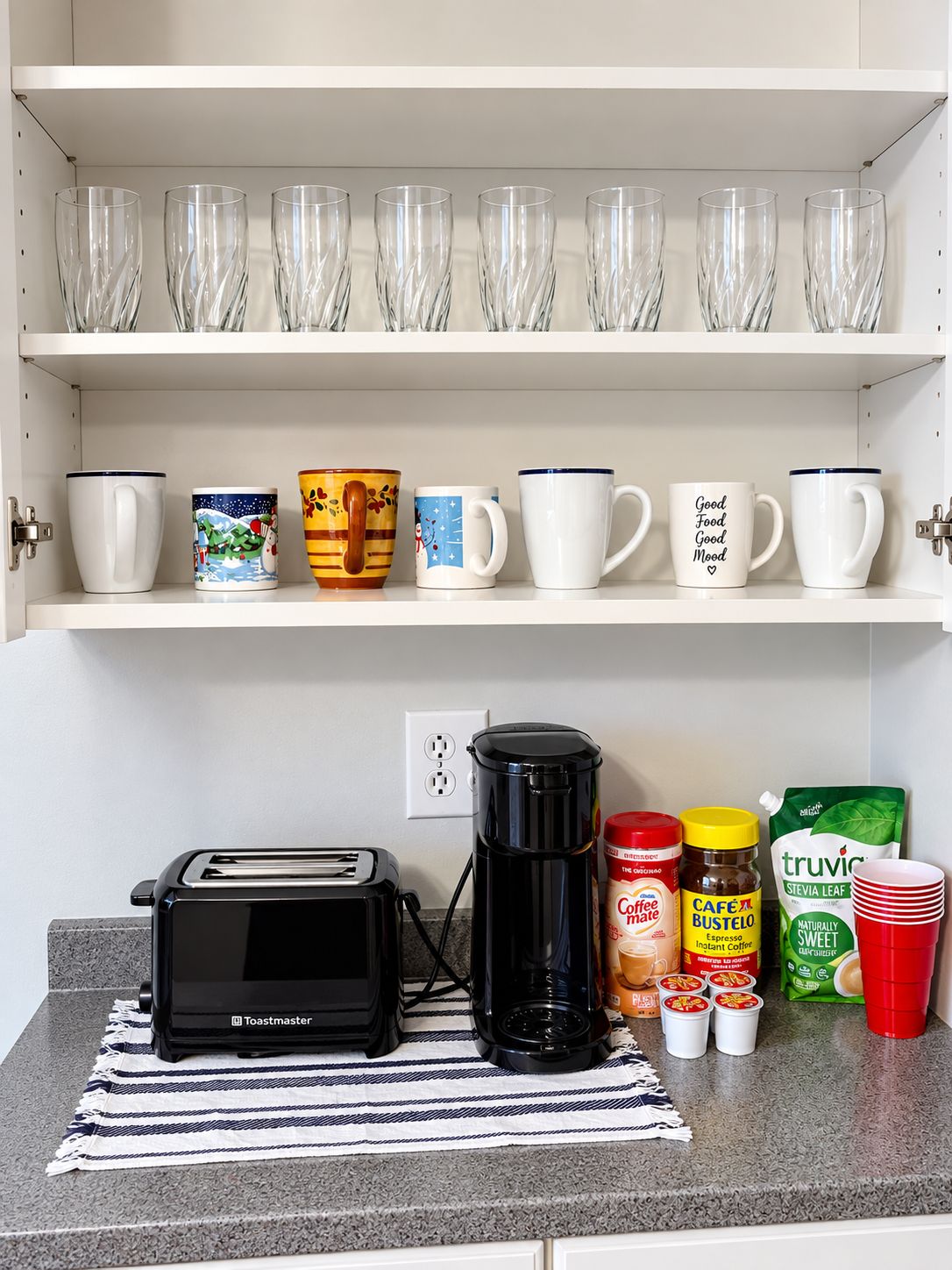 Una encimera de cocina con un tostador, una cafetera y varias tazas y recipientes para café.
