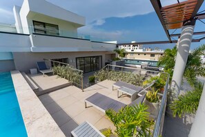 A modern outdoor pool area with lounge chairs and a glass balustrade. - Modern Piantini Stay Prime Location + Pool (Santo Domingo)