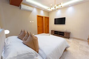 A bedroom with a bed, a TV mounted on the wall, a wooden wardrobe, and a ceiling light fixture. - Modern Piantini Stay Prime Location + Pool (Santo Domingo)