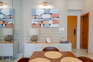 Ein modernes Interieur mit Esstisch, Stühlen, einer Couch und abstrakter Wandkunst.