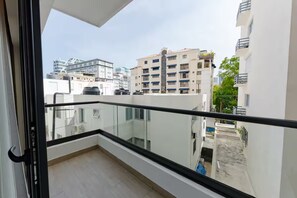 Ein Balkon mit Glasgeländer, der auf einen Wohnbereich mit mehreren Gebäuden blickt.