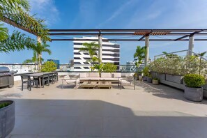 A rooftop terrace with outdoor seating, a grill, and potted plants. - Modern Piantini Stay Prime Location + Pool (Santo Domingo)