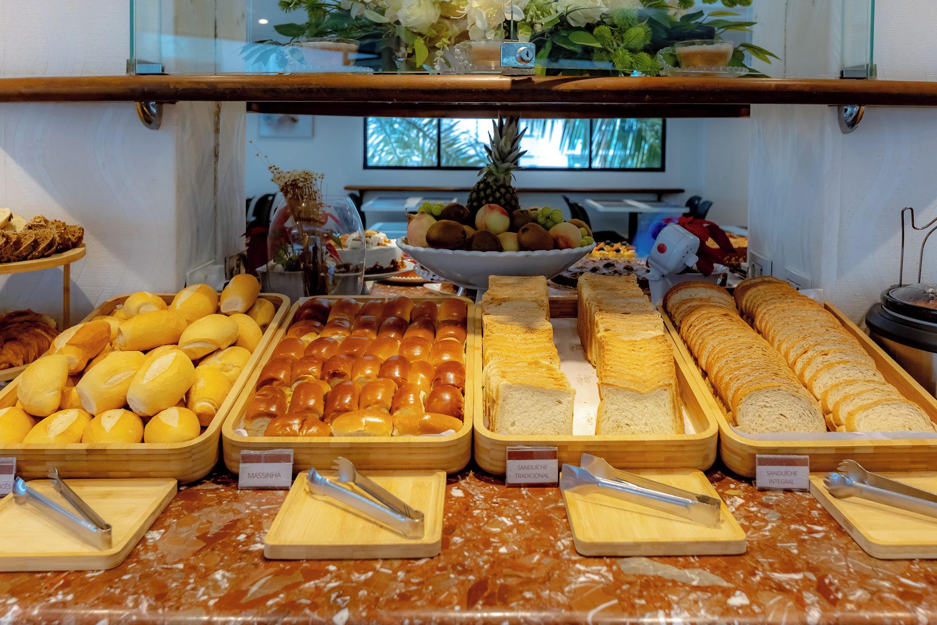 A buffet with various bread options and a decorative plant in the background.