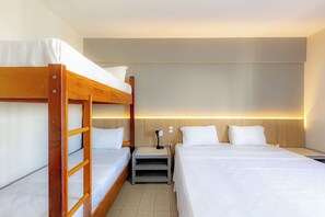 A hotel room with a bunk bed, a single bed, a bedside table with a lamp, and a wall-mounted light. - Central By Candeias (Balneário Camboriú)