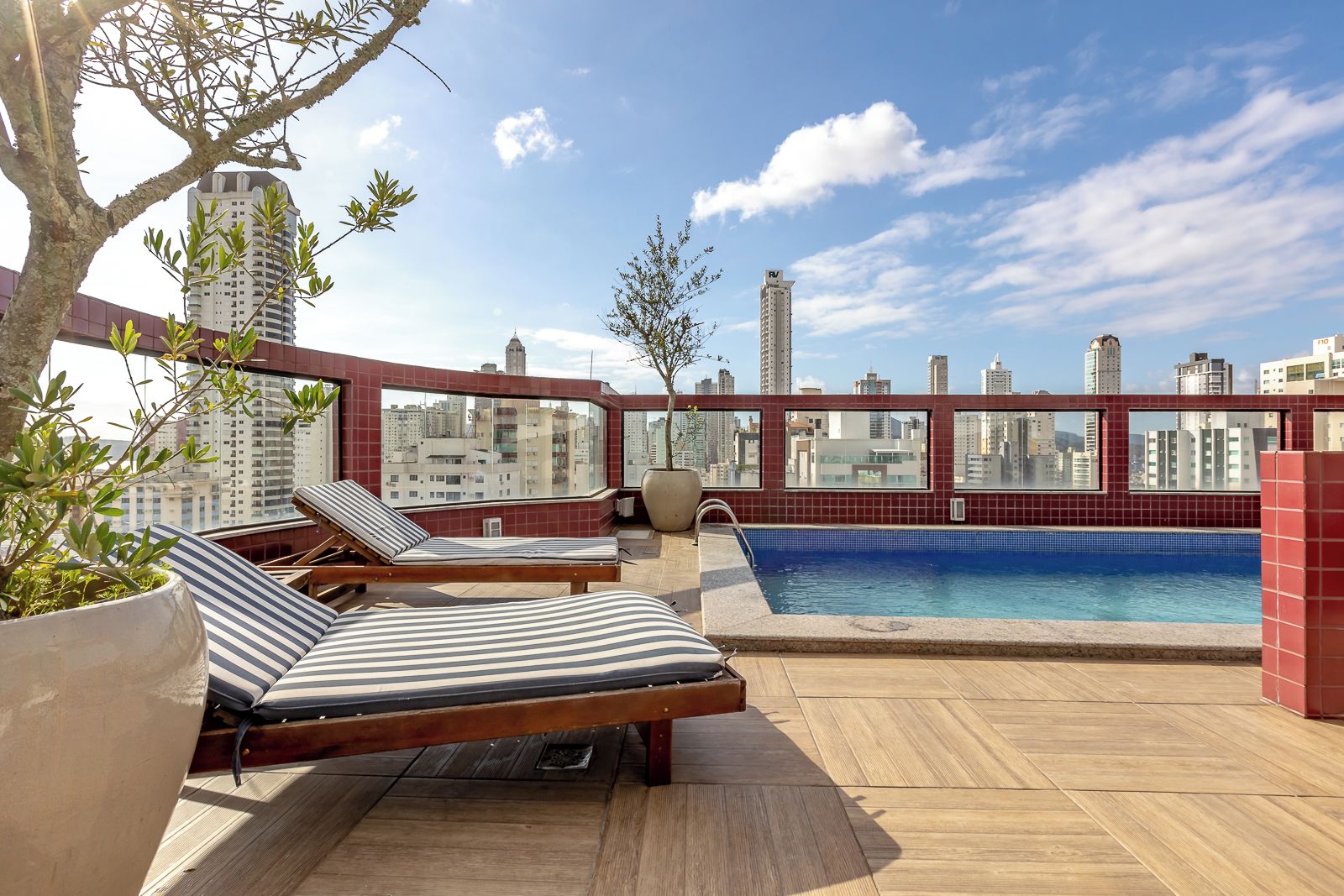 A rooftop terrace with a swimming pool, lounge chairs, and a view of the city skyline.