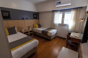 A hotel room with two beds, a desk, a chair, a lamp, and a window with curtains. - Recoleta Vibes Hotel (Buenos Aires)