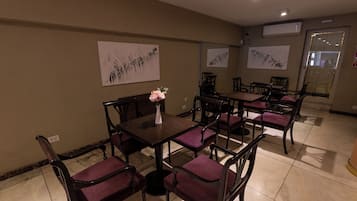 A dining area with a long table and chairs, a vase with flowers, and artwork on the walls.