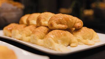 A plate of golden-brown pastries, likely croissants, arranged on a white rectangular plate.