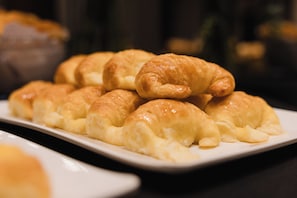 A plate of golden-brown pastries, likely croissants, arranged on a white rectangular plate. - Recoleta Vibes Hotel (Buenos Aires)