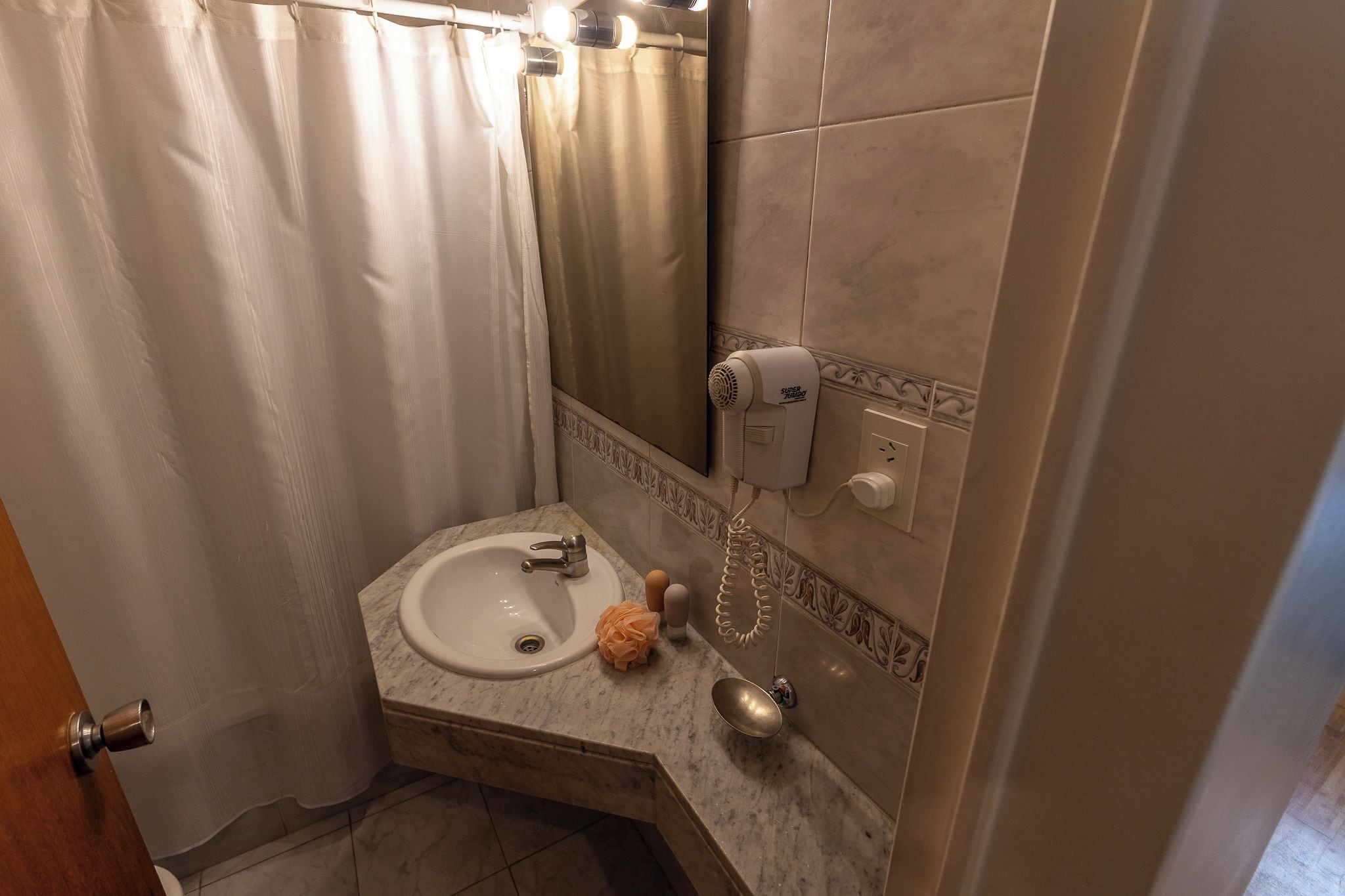 A bathroom with a sink, a hairdryer, and a mirror.