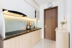 A modern kitchen with a built-in stove, a sink, and a clock on the wall. - 200m to West Lake | Balcony Studio | Private Kitchen & In-unit Washer/Dryer (Hà Nội)