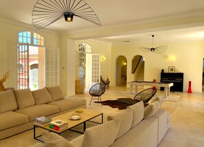 A spacious living room with a sofa, a coffee table, and a pool table. There is a piano and a staircase in the background. - Villa Aur a in 83220 (Le Pradet)