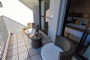 A balcony with wicker furniture, a glass door leading to a bedroom, and a potted plant. - Stay Hotel Plaza San Martin (Buenos Aires)