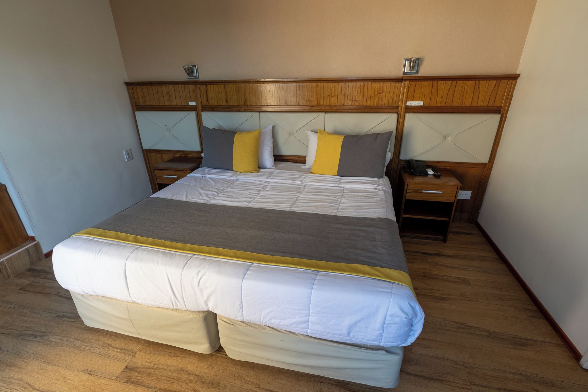 Ein Standard-Hotelzimmer mit einem großen Bett, Nachttischen und einem Holzkopfende.
