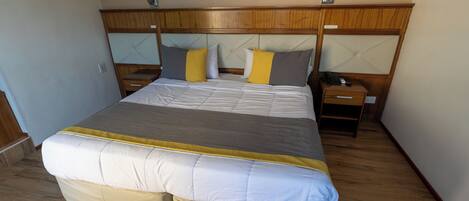 Ein Standard-Hotelzimmer mit einem großen Bett, Nachttischen und einem Holzkopfende.