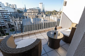 A balcony with wicker furniture, a table, and a bottle of wine. - Stay Hotel Plaza San Martin (Buenos Aires)