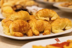 Un plato de pasteles dorados, probablemente cruasanes, dispuesto sobre un plato blanco.