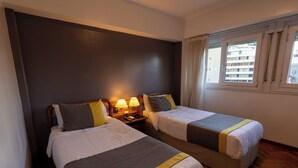 A hotel room with two beds, a nightstand with lamps, and a window with curtains. - STAY HOTEL PLAZA SAN MARTIN (Buenos Aires)