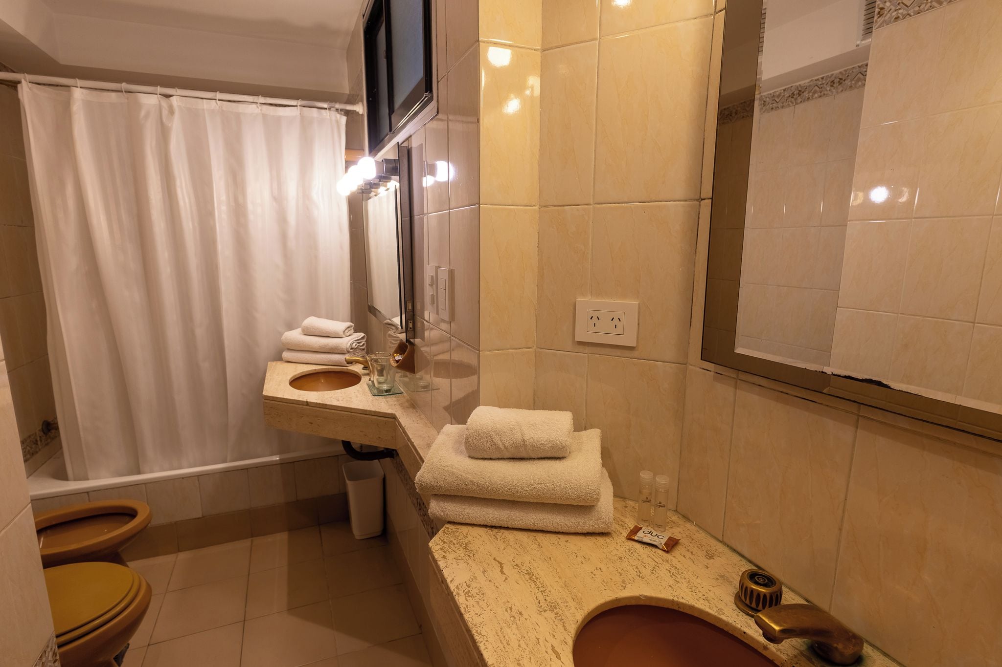 Un baño con bañera, lavamanos, espejo y retrete.