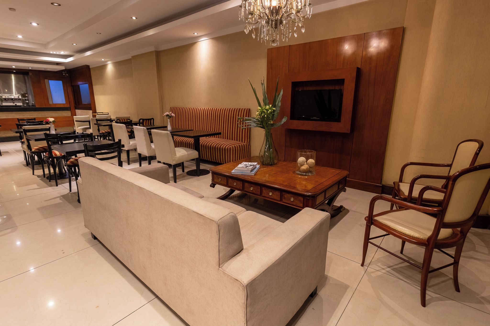 Un moderno vestíbulo de hotel con un sofá, zona de comedor y un televisor montado en la pared.