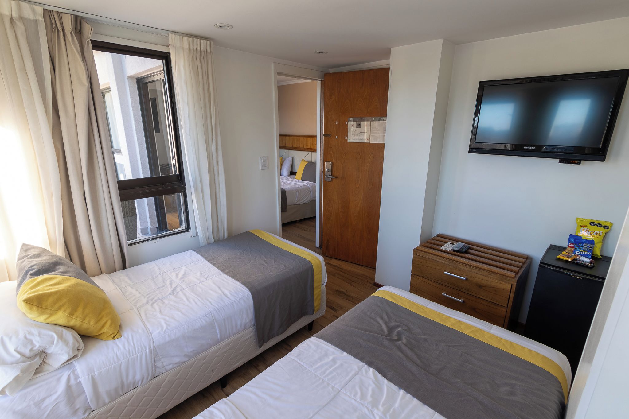 A hotel room with two beds, a television, a small desk, and a wardrobe.