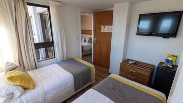 Habitación de hotel con dos camas, un televisor, un escritorio pequeño y un armario.