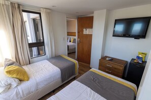 Habitación de hotel con dos camas, un televisor, un escritorio pequeño y un armario.