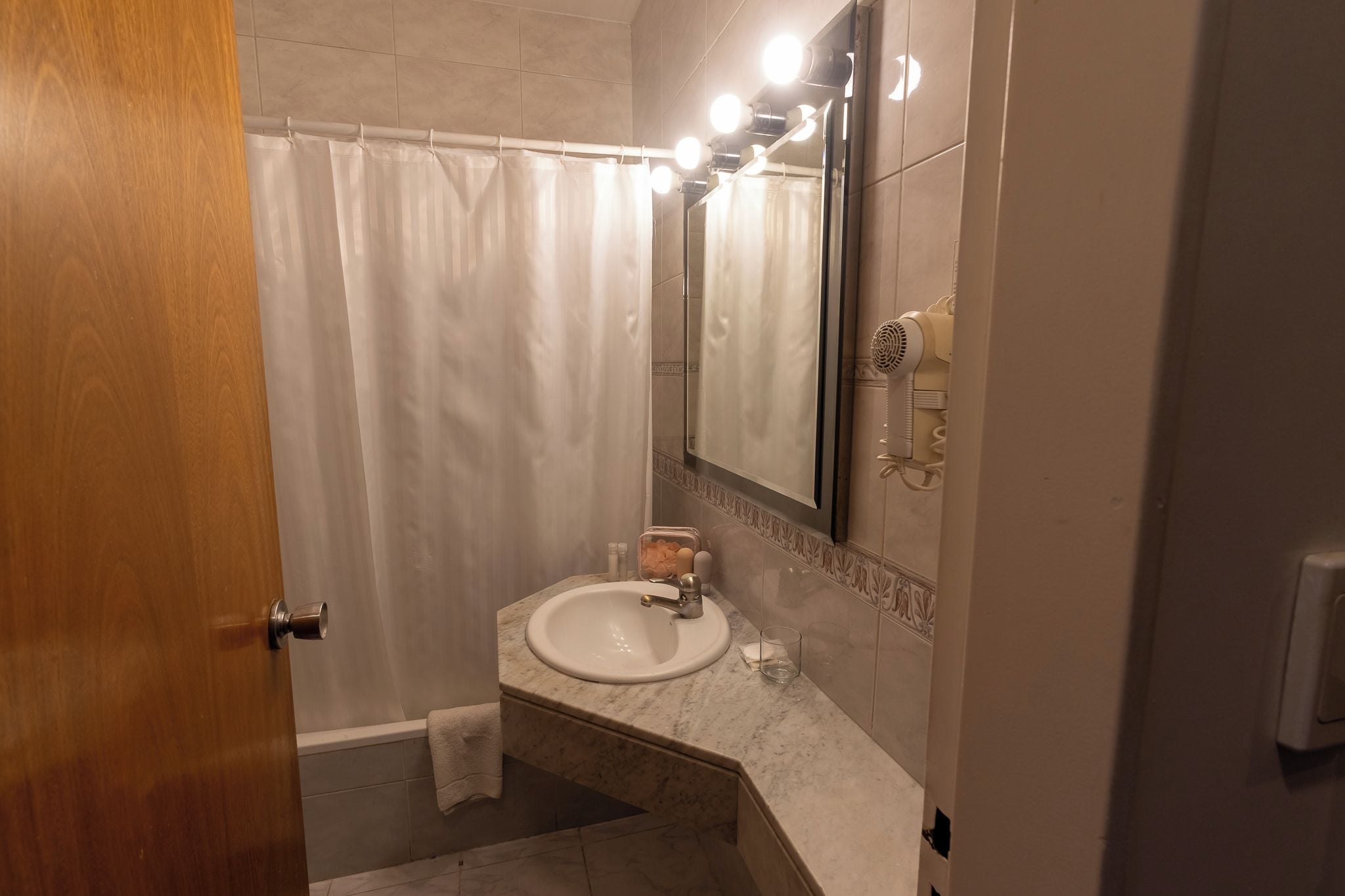Un baño con un lavamanos blanco, un espejo y una cortina de ducha.