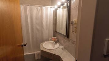Un baño con un lavamanos blanco, un espejo y una cortina de ducha.