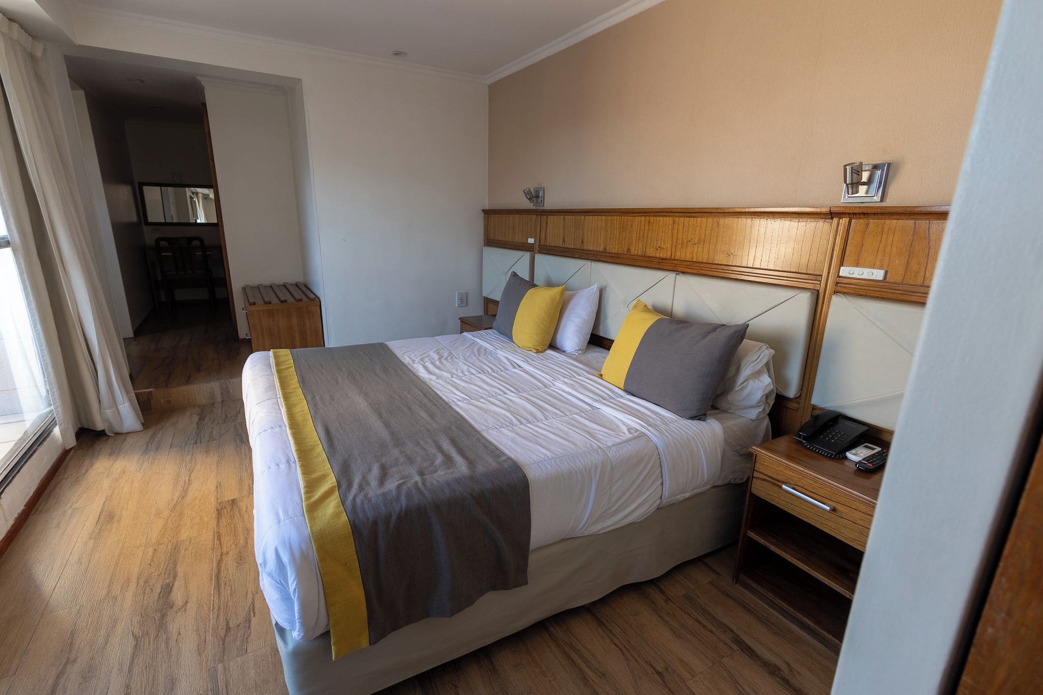 Ein Hotelzimmer mit Bett, Nachttisch und Blick auf den Flur.