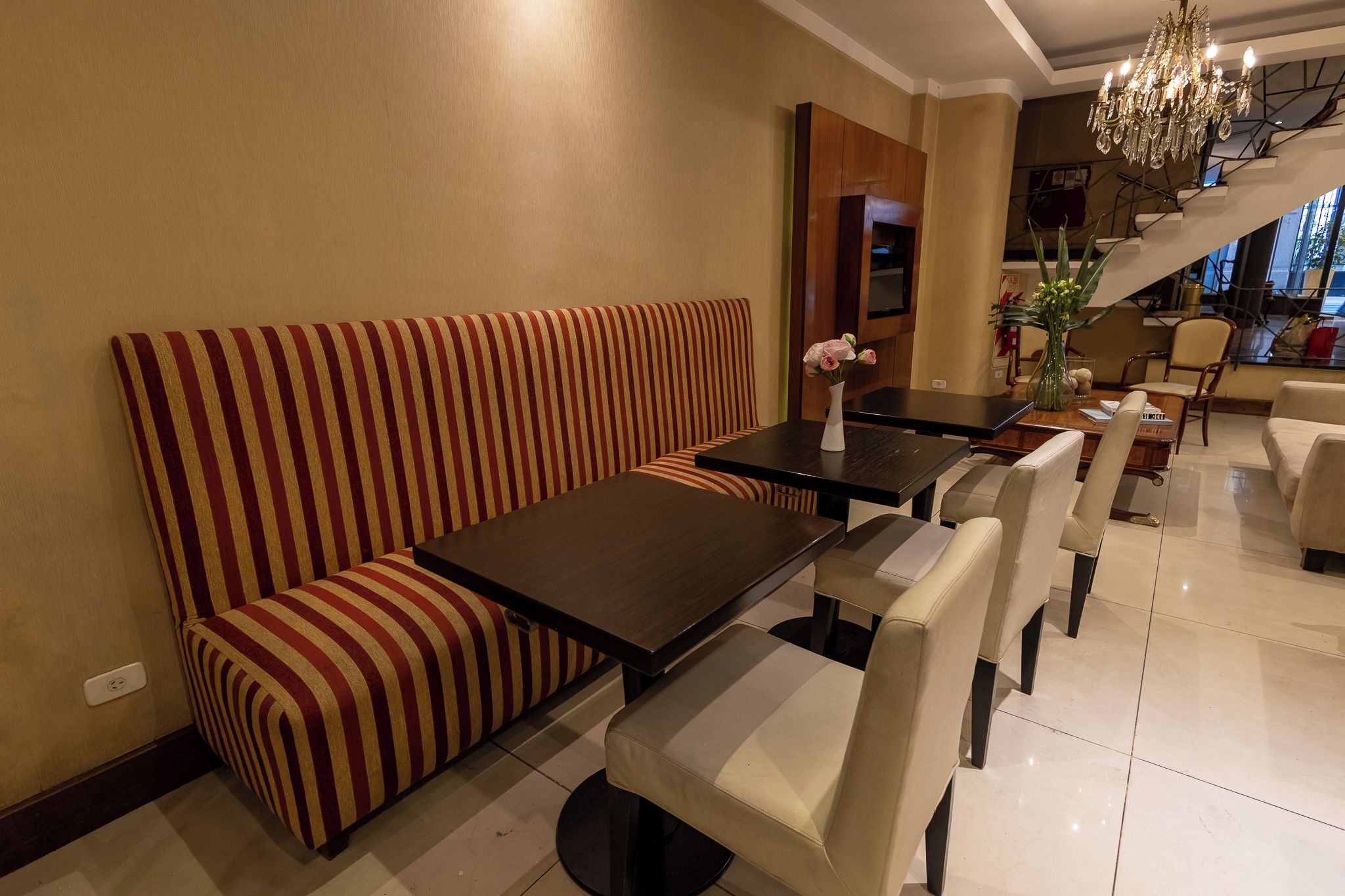 A dining area with a striped booth, a rectangular table, and chairs.