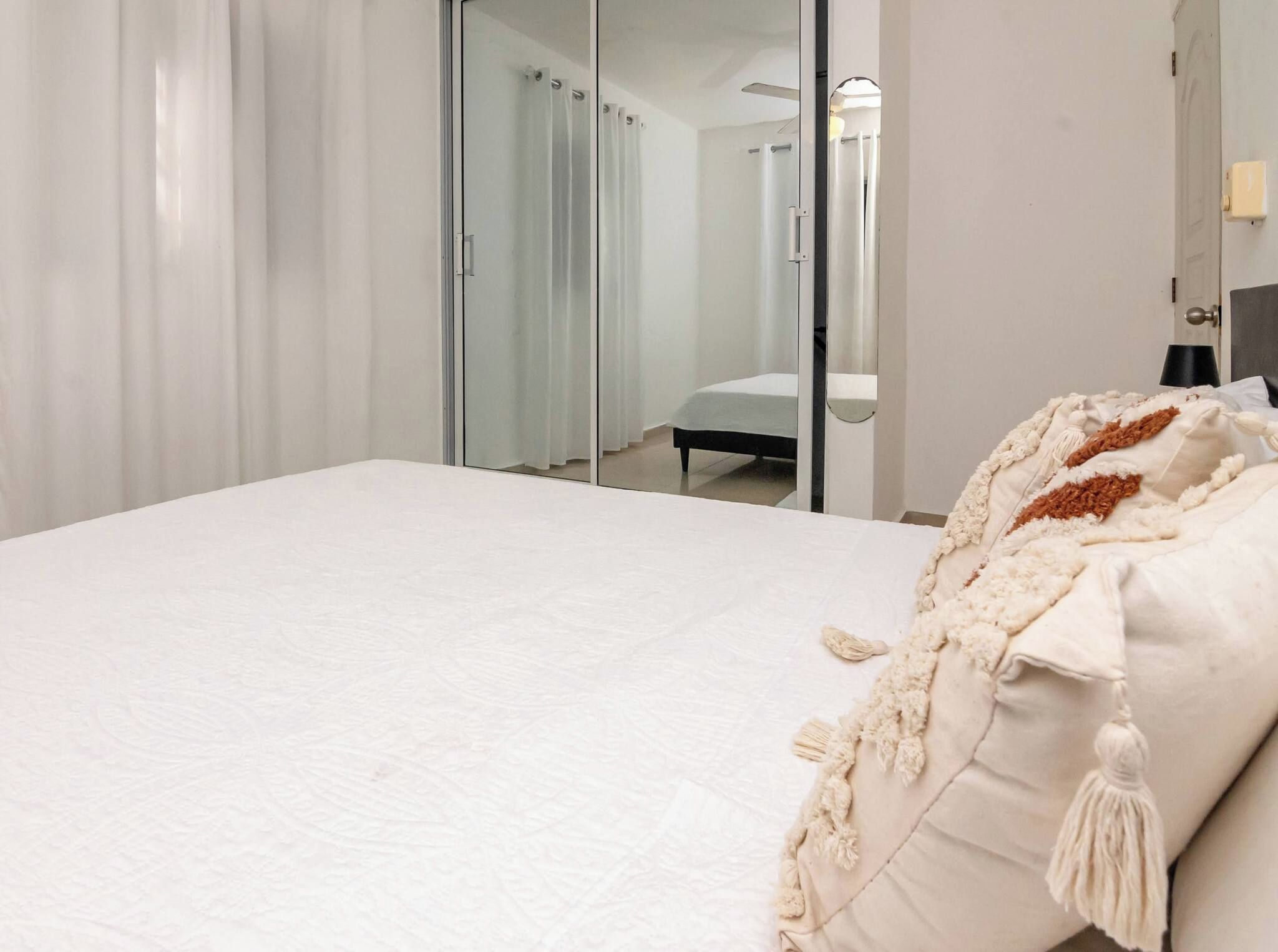 A hotel room with a bed, a mirror, and a door.