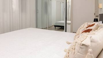 A hotel room with a bed, a mirror, and a door.