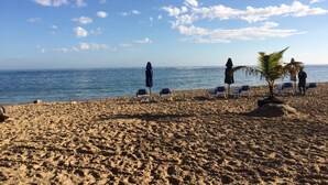 A beach with clear skies, calm sea, and several sun loungers. - Puerto Plata | 2BR | Jacuzzi | Terrace | Modern & Central (Puerto Plata)