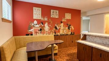Una habitación con suelo de parqué de madera, un sofá color beige, una mesa con patas de metal y una pared de acento roja con obras de arte enmarcadas.