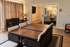 A dining area with a long table, cushioned chairs, a bench, and a chandelier.