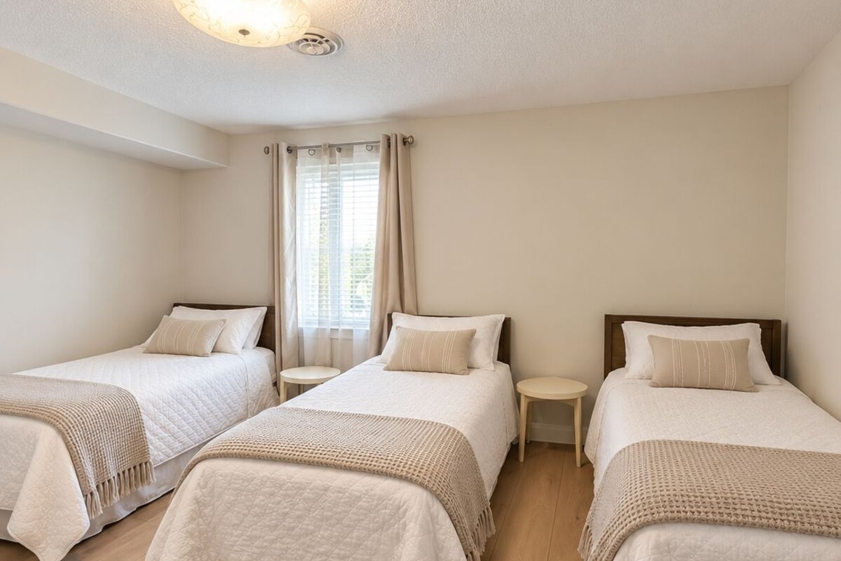A hotel room with three single beds, a small table between each bed, and a ceiling light fixture.