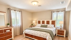 A bedroom with a bed, nightstands, a dresser, and a ceiling light.