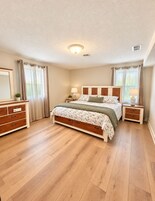 Quarto com cama, mesas de cabeceira, cômoda e luminária de teto.