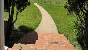 A pathway leading to a grassy field with a clear sky.