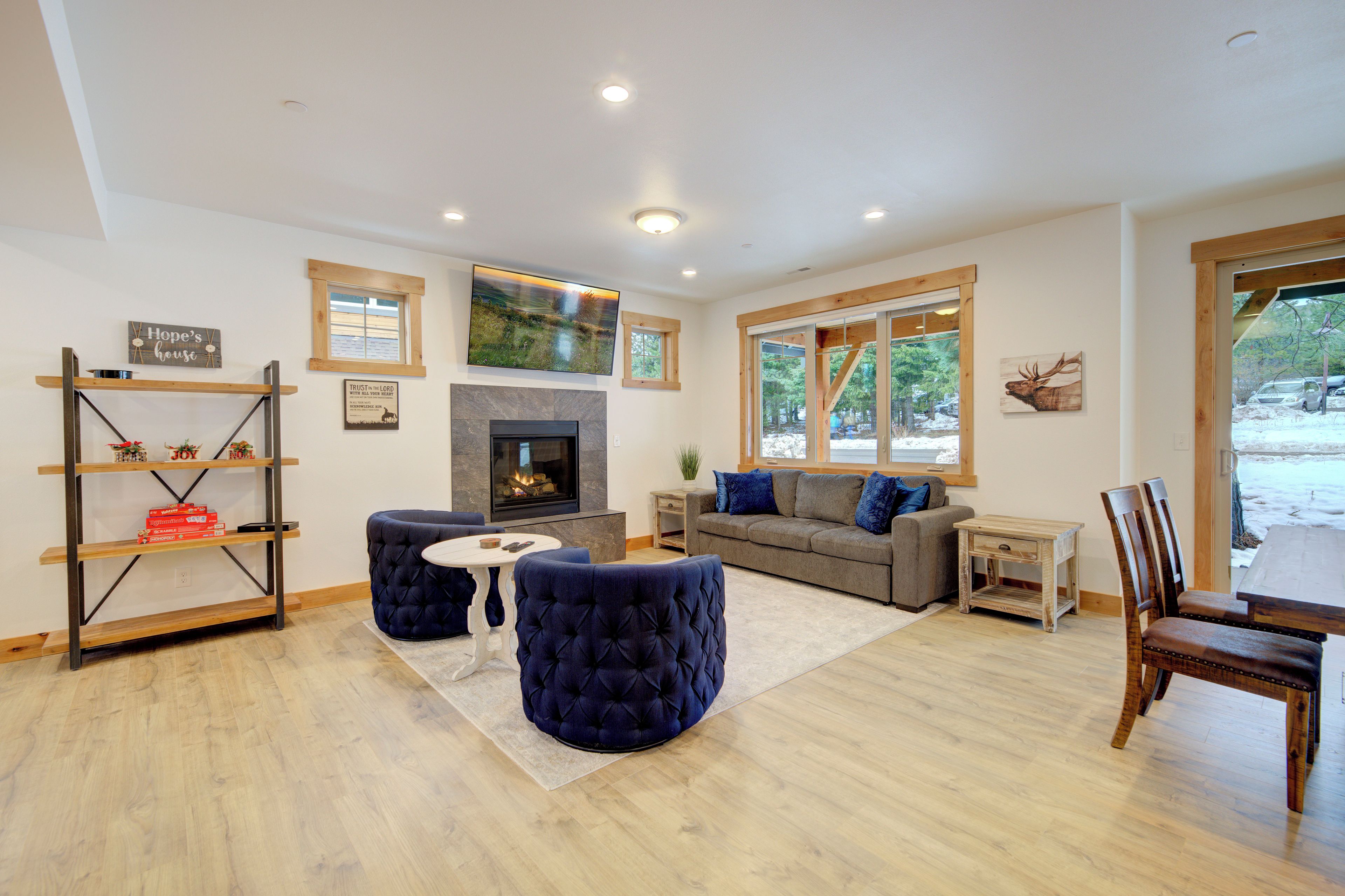 A modern living room with a fireplace, a sofa, ottomans, and a dining area with chairs.
