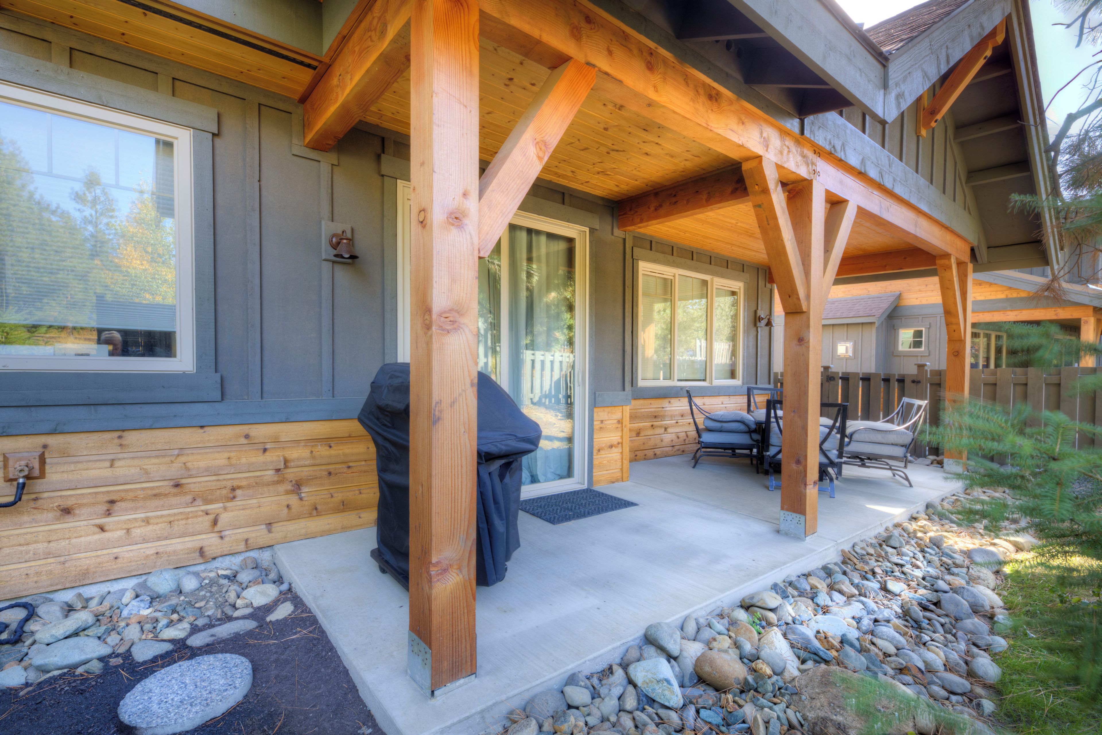 A covered outdoor seating area with a stone pathway leading to a wooden deck.