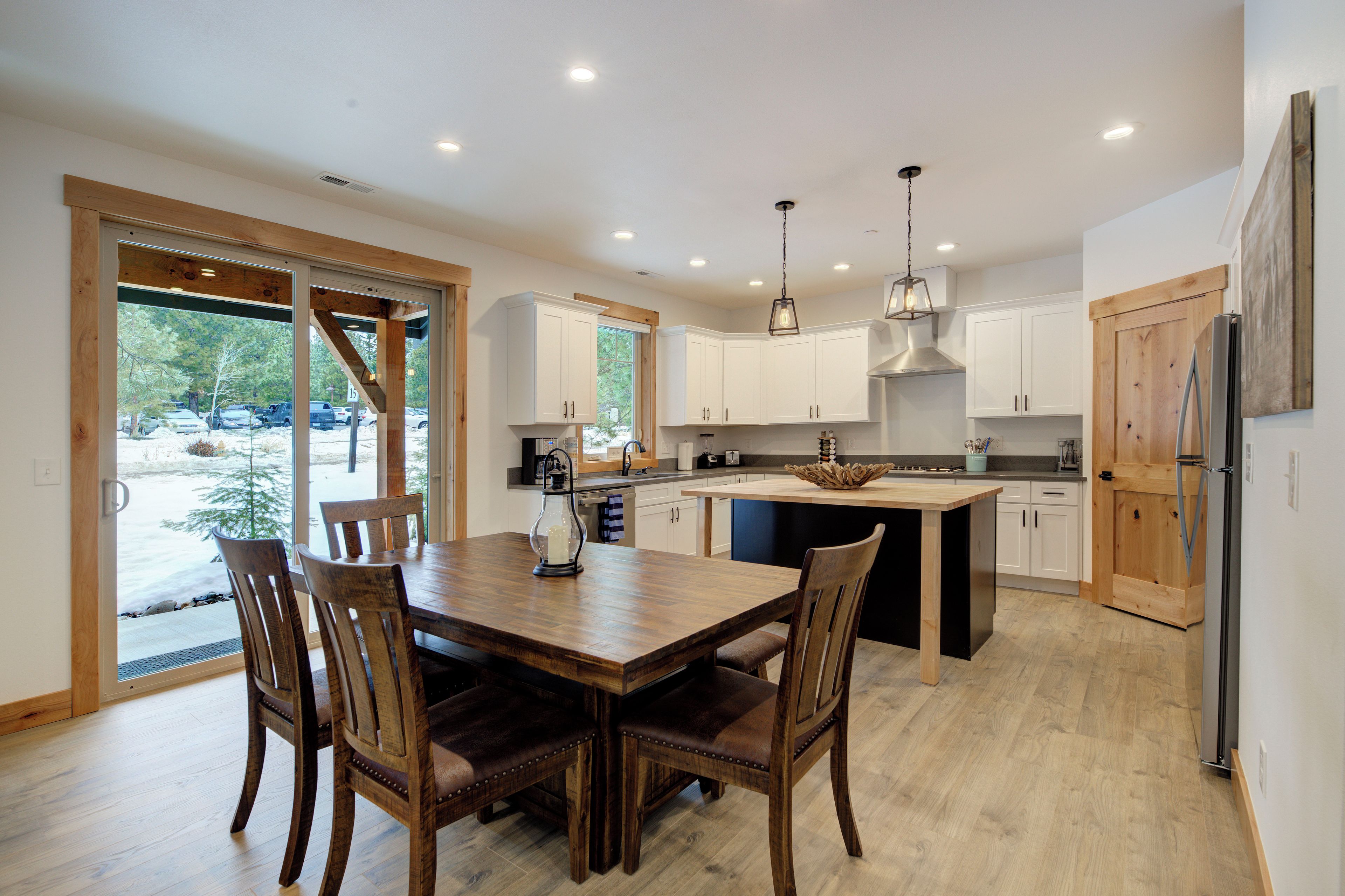 A modern kitchen with wooden cabinetry, a central island, and a dining area with a wooden table and chairs.