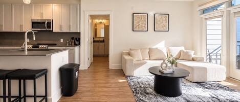 A modern kitchen with a central island, bar stools, and a trash can.