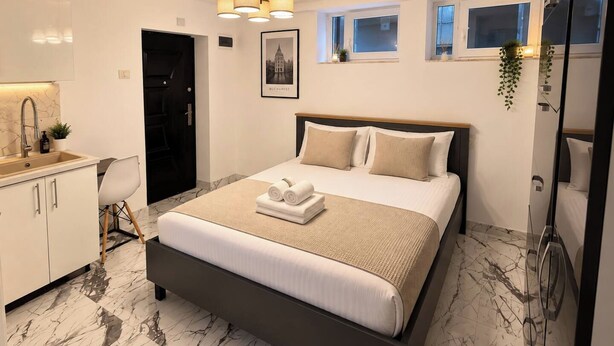 Een moderne hotelkamer met een groot bed, een badkamer met douche, wastafel en een klein raam.