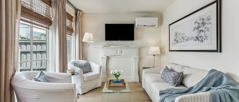 A living room with a fireplace, a flat-screen TV, and a large framed artwork on the wall.