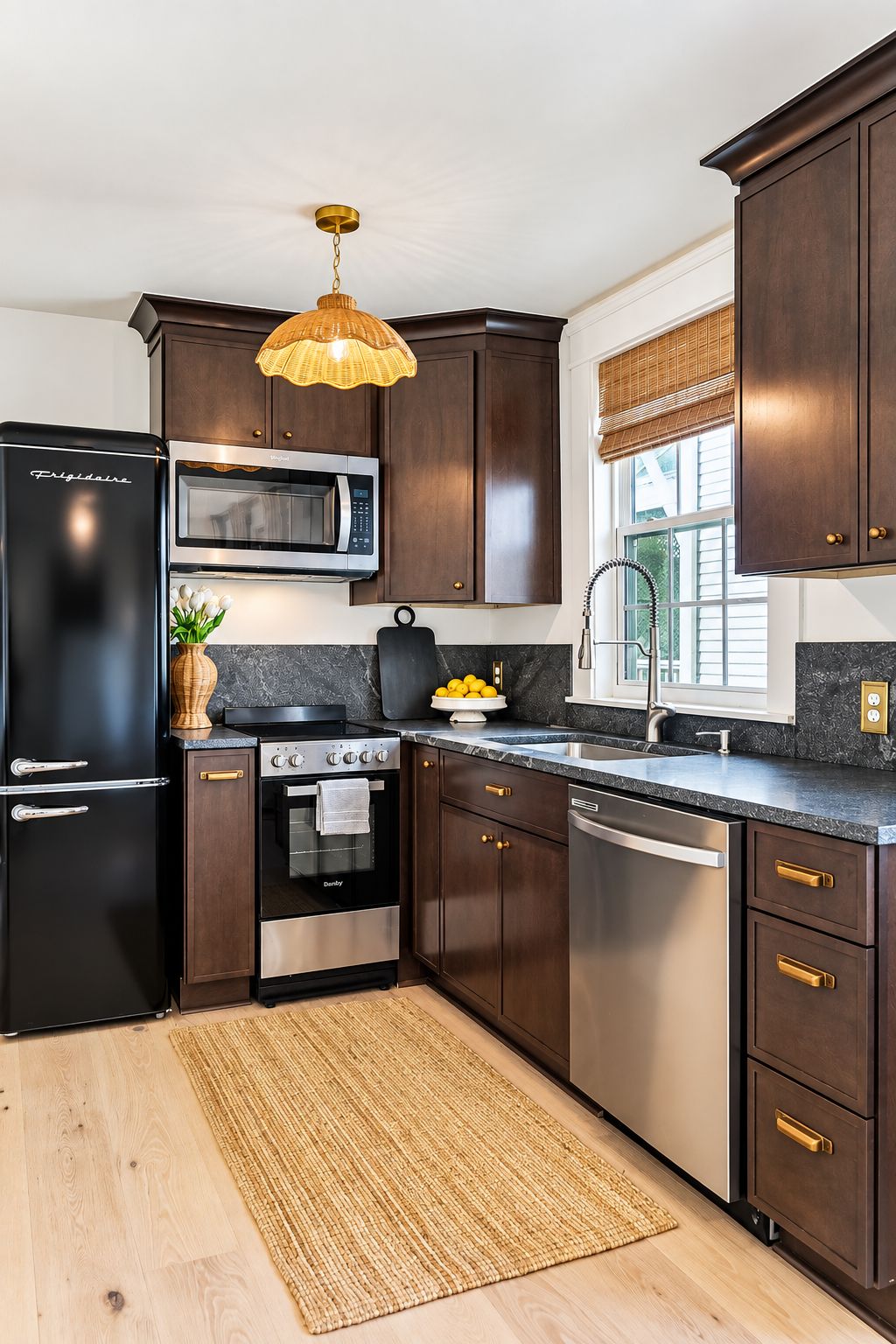 A modern kitchen with dark wood cabinets, stainless steel appliances, and a woven rug on the floor.